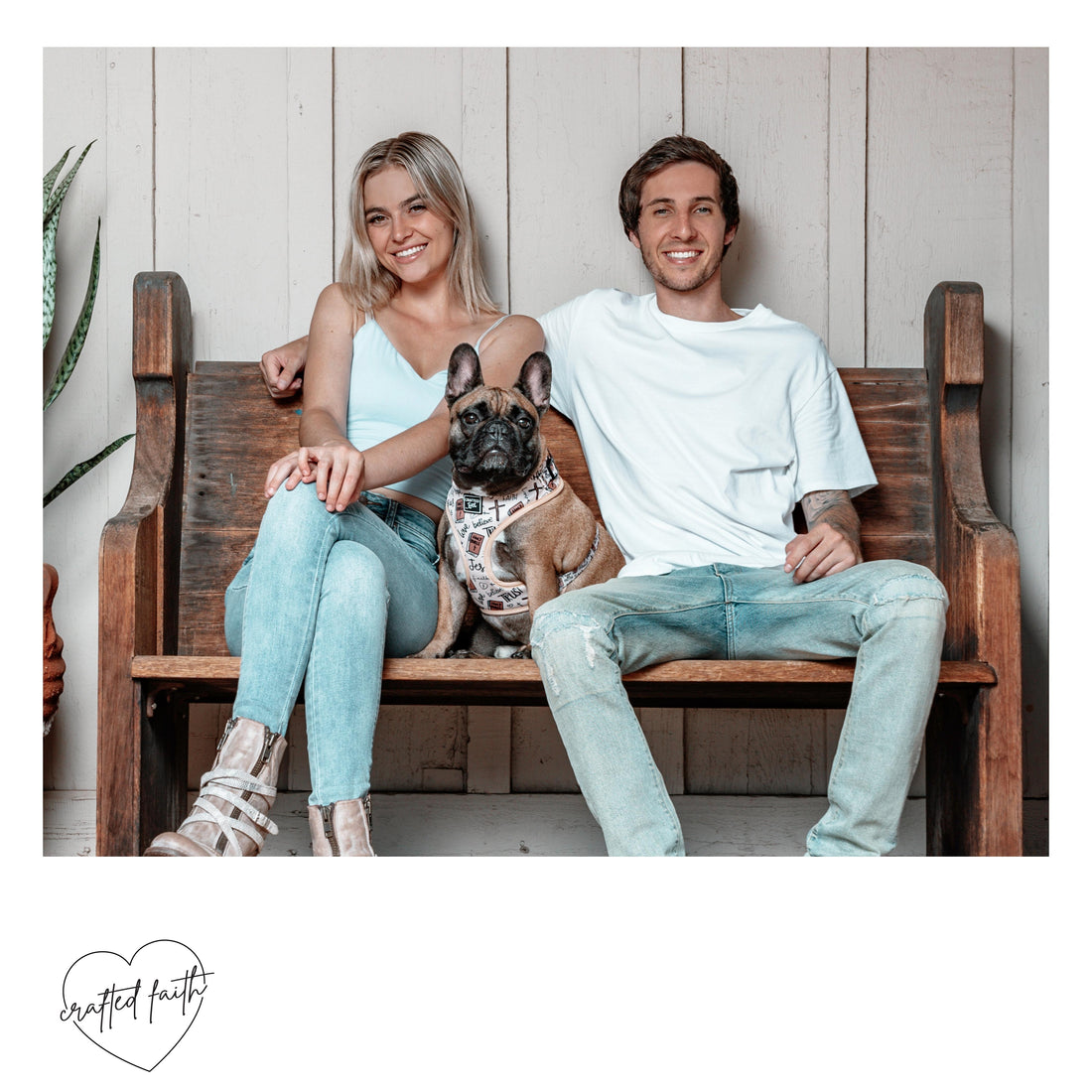 A male, female and French bulldog sitting on a wooden bench.