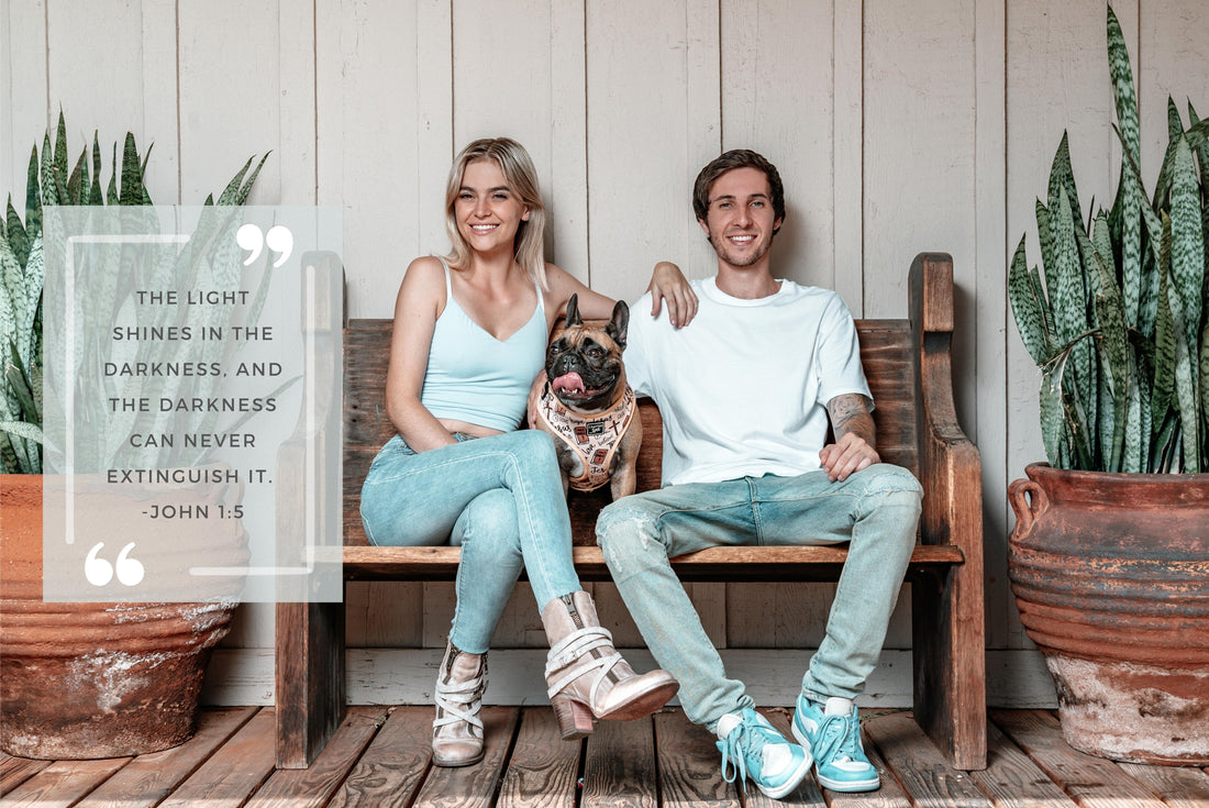 A male, female and French bulldog sitting on a wooden bench.